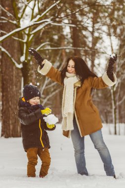 Happy family in warm clothing. Smiling mother and son playing fun game outdoor. The concept of winter activities