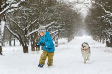 boy running away from dogs or husky outdoors in winter day
