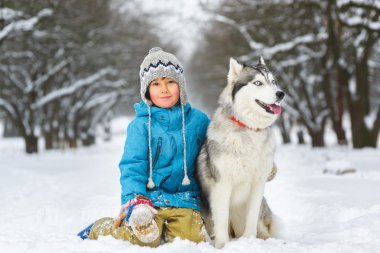 happy boy hugging dog or husky outdoors in winter day