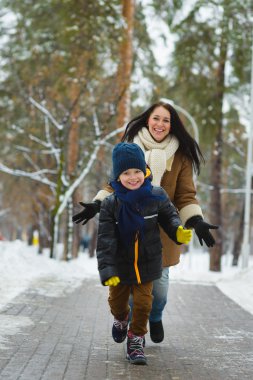 Kış giyim mutlu bir aile. Gülümseyen oğlu annesi açık uzak çalışır