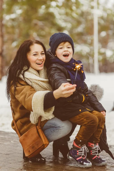 happy mother and cheerful son keep a sparklers or bengal fires outdoor