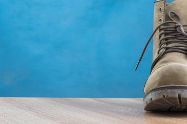 Ahşap yüzey ve mavi arka plan üstünde Patina deri çizme