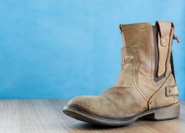 Ahşap yüzey ve mavi arka plan üstünde Patina mühendis deri çizme