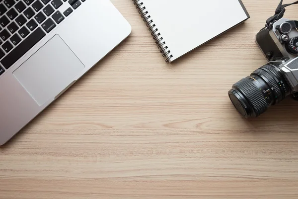 Office tabel met laptop, notitieboekje en camera film. — Stockfoto