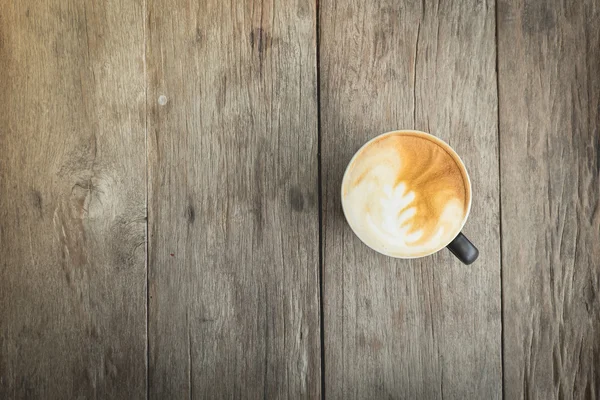 Xícara de café com arte latte em uma mesa de madeira. Tábuas de madeira velhas . — Fotografia de Stock