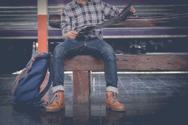 harita ile oturan adam. tren istasyonunda seyahat çantası.vintage filtre etkili