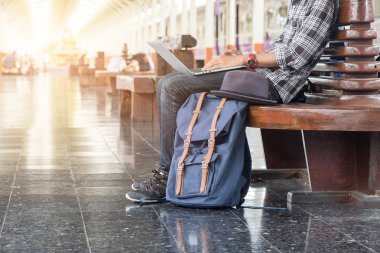 adam dizüstü bilgisayar ile oturuyor. tren istasyonunda seyahat çantası.vintage filtre etkili .