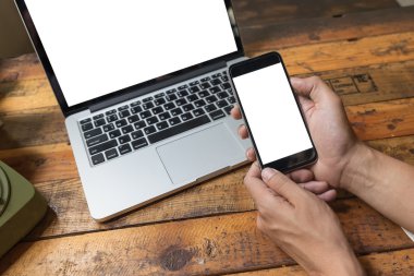 Eski ahşap masada izole ekranlı dijital dizüstü bilgisayar ve beyaz akıllı telefon