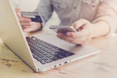 Online ödeme, kredi kartı tutan ve vintage ile online alışveriş için akıllı telefon kullanarak adamın elleri etkisi filtre.