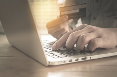 Online ödeme, kredi kartı tutan ve vintage ile online alışveriş için dizüstü bilgisayar kullanarak adamın elleri etkisi filtre.