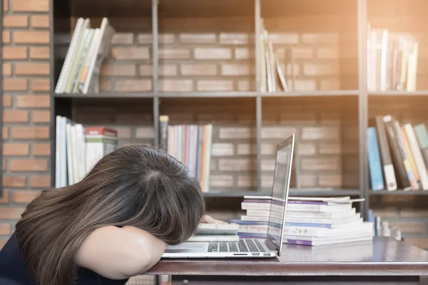 Уставшая студентка в очках спит на книгах в библиотеке — стоковое фото
