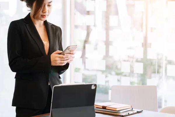 Businesswoman working on smart tablet at office while using smartphone for social or chat