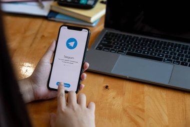 CHIANG MAI, THAILAND, 23 HAZİRAN 2021: Ekranda sosyal ağ servisi telgrafı olan iPhone 12 ile el ele tutuşan kadın. iPhone 12 Apple tarafından oluşturuldu ve geliştirildi..