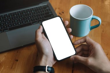 Görüntü görüntüsü boş beyaz ekran cep telefonu. Erkekler el ele mesajlaşırken evdeki koltukta rahat bir şekilde rahat bir şekilde oturuyorlar. Reklam metni için arkaplan boşluğu. İnsanlar pazarlama ve teknoloji ile iletişime geçiyor.