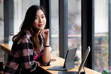 Kafede dijital tabletle çalışan Asyalı genç bir portre.