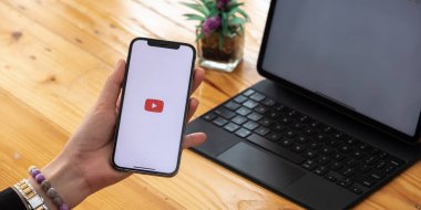 CHIANG MAI, THAILAND - 7 MAR 2021: Apple iPhone 12 uygulaması ile el ele tutuşan kadın ekranda canlı yayın medyası ve video sağlıyor