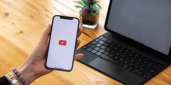 CHIANG MAI, THAILAND - 7 MAR 2021: Apple iPhone 12 uygulaması ile el ele tutuşan kadın ekranda canlı yayın medyası ve video sağlıyor