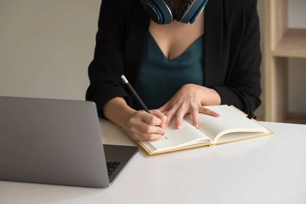 Женщина делает заметки, сидя за рабочим столом во время изучения онлайн смотреть подкаст вебинар на ноутбуке прослушивания учебного курса конференции, обучения концепции. — стоковое фото