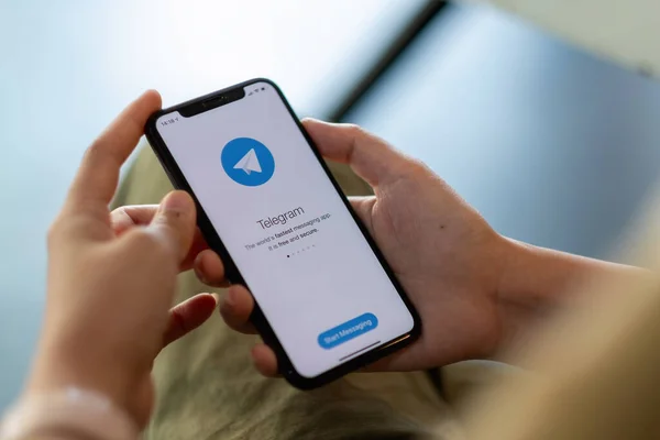 CHIANG MAI, THAILAND - APR 11, 2021: Kvinna hand håller iPhone X med social nätverkstjänst Telegram på skärmen. iPhone 10 skapades och utvecklades av Apple inc — Stockfoto
