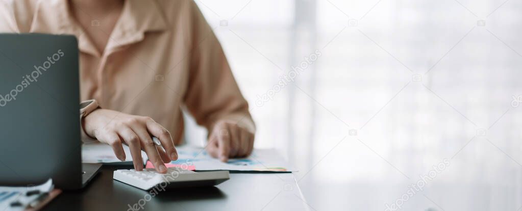 Business woman using calculator for do math finance on wooden desk in office, tax, accounting, statistics home accounring concept.