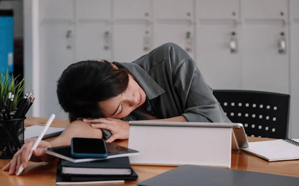 Переутомленная деловая женщина спит на столе в офисе. Молодая измученная девушка работает из дома. Женщина с ноутбуком. Предприниматель, бизнес, внештатная работа, студент, стресс, работа из концепции дома. — стоковое фото
