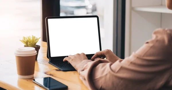 Boş ekran tabletine ve ofis malzemelerine basit bir çalışma alanında yazı yazan genç profesyonel iş kadını görüntüsü..