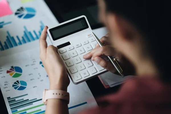 Acima vista de accouting mulher consultor segurando caneta e usando calculadora com relatório financeiro sobre mesa de madeira em casa. conceito de pesquisa freelance, tributária, contábil, estatística e analítica — Fotografia de Stock