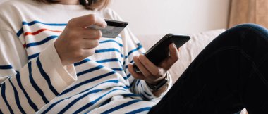 Çevrimiçi alışveriş ödemesi, akıllı telefon ve kredi kartı tutan kadınların elleri ve evden online alışveriş