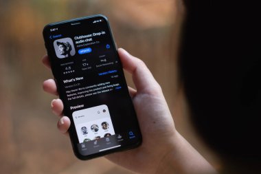 CHIANG MAI, THAILAND, 13 MAR 2021: Kablolu Kulaklıklı Kadın elinde Smartphone ve kulüp binası ile ekranda sesli sohbet uygulaması var. Alpha Exploration Co. 'nun 2020 yılında başlattığı yeni sosyal ağ