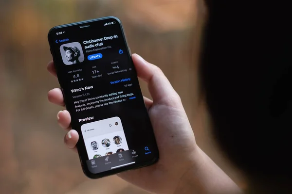 CHIANG MAI, THAILAND, 13 MAR 2021 : Woman in Wired Headphones holding Smartphone with Clubhouse drop in audio chat application on screen. New social network launched in 2020 by Alpha Exploration Co — Stock Photo, Image