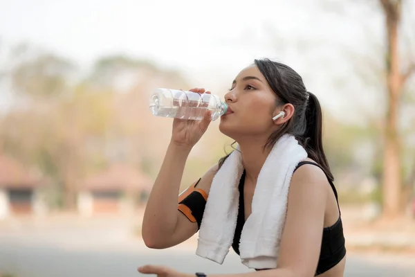 Hermosa atleta de fitness mujer beber agua después de hacer ejercicio en el amanecer mañana verano en el parque — Foto de Stock