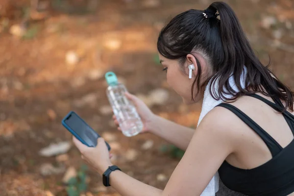 Trött fitness kvinna svettas tar tar en paus lyssna på musik på telefon efter svår träning — Stockfoto