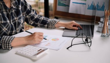 Finansal konsepte danış. İşadamı kağıt işlerini işaret ediyor ve dizüstü bilgisayar kullanıyor.