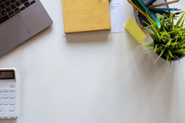 Boş ekran bilgisayarı, dizüstü bilgisayarı, fare, kahve fincanı ve diğer ofislerle dolu beyaz ofis masası..
