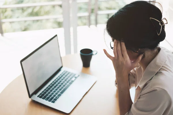 Уставшая азиатская деловая женщина с головной болью от работы ноутбука чувствует головную боль в офисе, чувствует себя больным на работе — стоковое фото