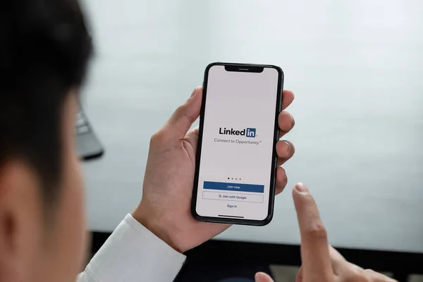 CHIANG MAI, THAILANDIA, APR 06, 2019: Un uomo detiene sullo schermo Apple iPhone Xs con applicazione LinkedIn LinkedIn è un'app per la condivisione di foto per smartphone — Foto Stock