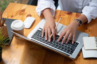 Kafede dizüstü bilgisayar kullanan bir kadın çevrimiçi öğrenim için klavye yazan bir kadının eli..