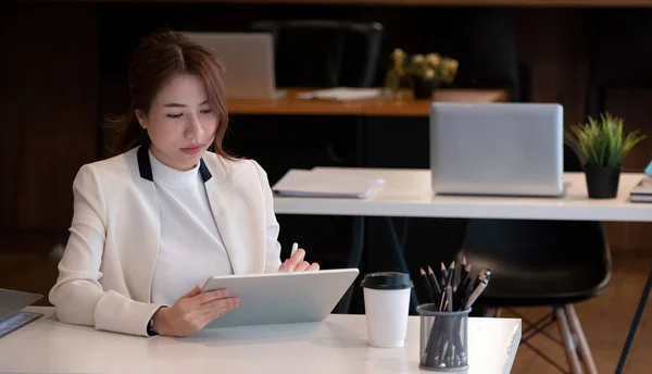 사무실에서 디지털 타블렛을 사용하는 사업 복을 입고 있는 젊은 이시아 여성, 사업 자금을 위해 일하는 여성. — 스톡 사진