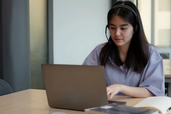 Azjatycka dziewczyna w słuchawkach mają połączenie wideo odległe klasy z nauczycielem za pomocą laptopa, młody uczeń noszenie słuchawki z nauczycielem, nauka online na komputerze, koncepcja wychowania domowego. — Zdjęcie stockowe