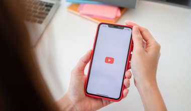 CHIANG MAI, THD - MAY 20, 2021: Woman hand holding Apple iPhone 11 with App YouTube provides streaming media and video on the screen