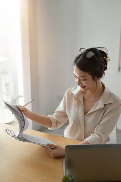 オフィスのノートパソコンで事業報告書を分析する女性アジア系ビジネスウーマン。縦射 — ストック写真