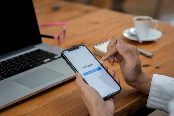 CHIANG MAI, TAILANDIA - 30 DE MAYO DE 2021: Una mujer sostiene Apple iPhone 11 con aplicación de Instagram en la pantalla de la cafetería. Instagram es una aplicación para compartir fotos para teléfonos inteligentes. — Foto de Stock