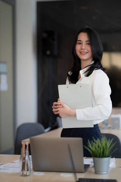 Retrato de sucesso jovem mulher de negócios asiática em pé no escritório, colegas de fundo — Fotografia de Stock