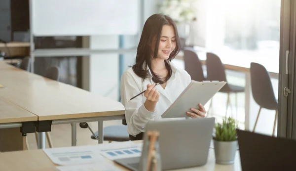 Portrait d'une jeune femme d'affaires asiatique prospère travaillant avec un rapport financier dans une salle de réunion. — Photo