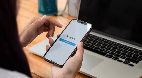 CHIANGMAI, THAILAND - MAY 3, 2021: Жінка тримає iPhone 11 з додатком Instagram на екрані за столом, з "єднуючись — стокове фото