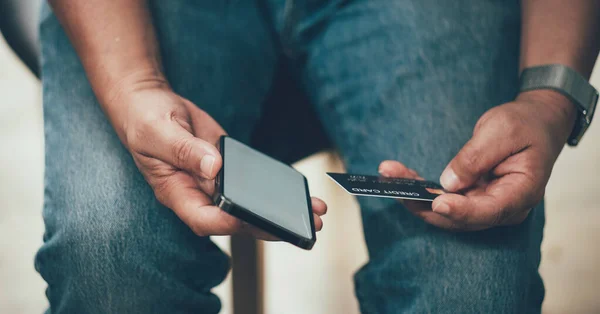 Онлайн-оплата, Mans hands holding a credit card and using smarphone for online shopping at coffee cafe shop — стоковое фото