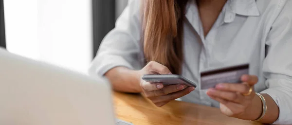 Close up asian woman using smartphone and credit card for online shopping at home with copy space. E-payment technology, shopaholic lifestyle, or mobile phone financial application concept. — ストック写真