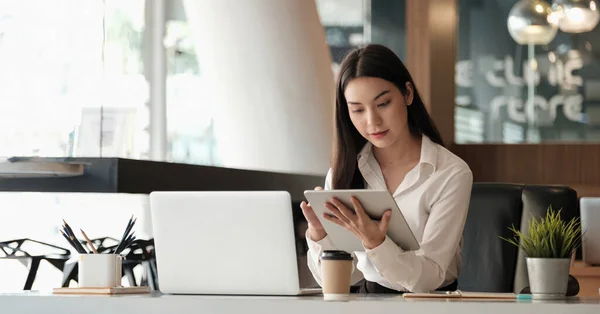 Mooie aziatische zakenvrouw met behulp van tablet en laptop tijdens het werken in het kantoor — Stockfoto