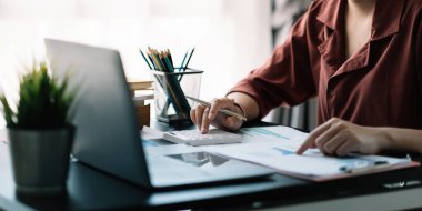 Hesap makinesi ve dizüstü bilgisayar kullanan iş kadını ofis ve iş geçmişinde, vergi, muhasebe, istatistik ve analitik araştırma kavramında ahşap masada finans yapıyor.