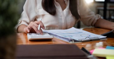 Finans Tasarruf Bankası Konsepti, Erkek muhasebeci gelir hesapları ve ev ofisteki hesap makinesiyle finansal grafik verilerini analiz